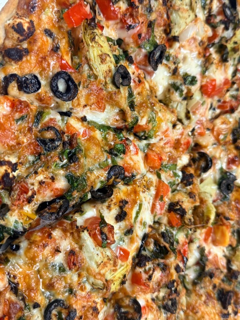Veggie pizza with black olives, artichoke, peppers and leafy greens at Cravings and Delight, a family restaurant near Allard Edmonton