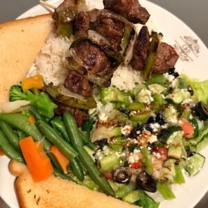 Beef souvlaki plate with rice, Greek salad, vegetables and garlic toast at Cravings and Delight