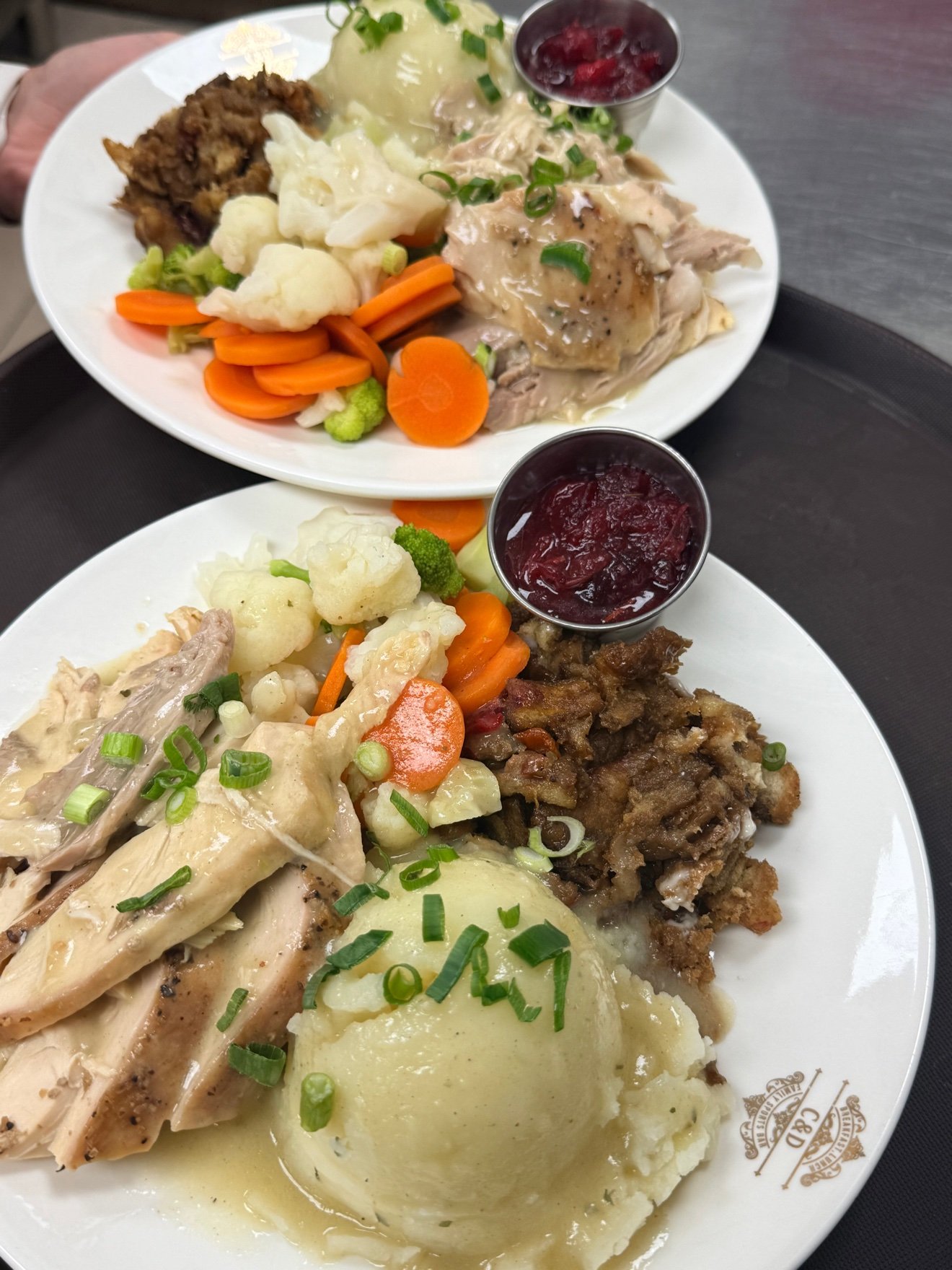 Two plated roast turkey dinners with mashed potatoes, vegetables, stuffing and cranberry sauce at Cravings and Delight