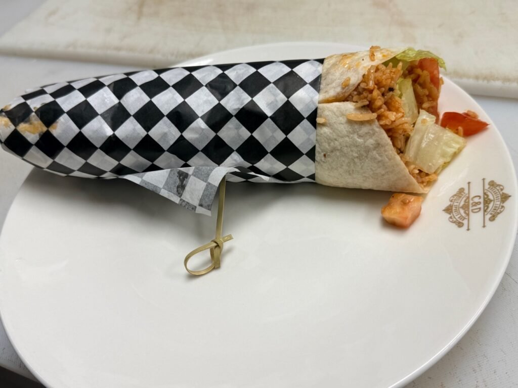 Donair wrap with rice and salad in checkered paper at Cravings and Delight, a family restaurant near Glenridding Edmonton